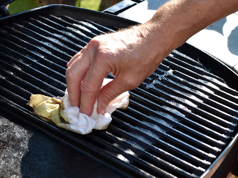 Grilling meat with cleaning cloth on a BBQ grill for delicious outdoor cooking and barbecue.