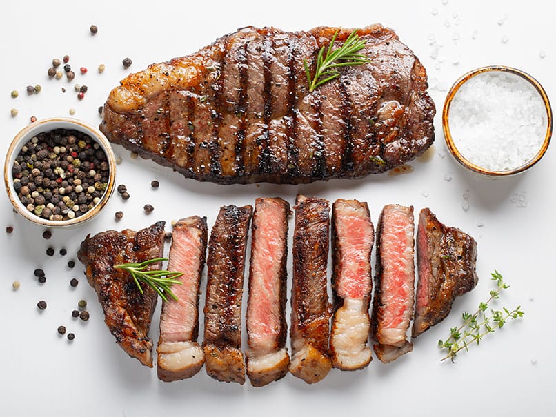 Juicy grilled steak with herbs, sea salt, and peppercorns for optimal flavor and grilling perfection.