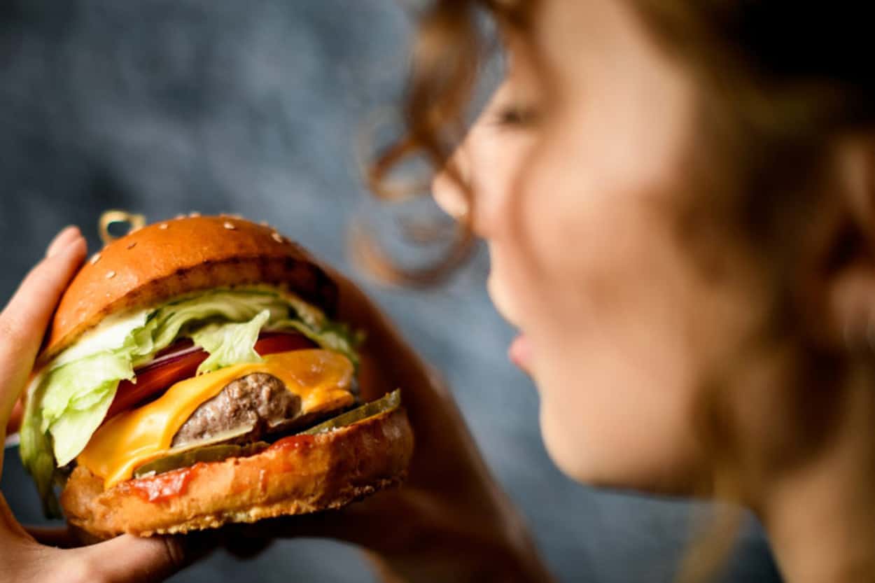 Juicy cheeseburger with fresh vegetables on a toasted bun, close-up, food photography.