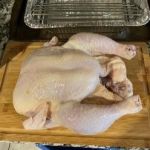 Raw whole chicken on cutting board for precise temperature cooking.