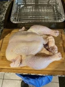 Raw whole chicken on cutting board for precise temperature cooking.