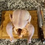 Raw whole chicken on cutting board for cooking or roasting.
