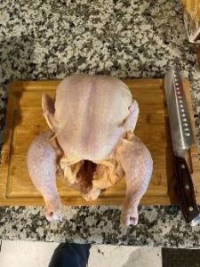 Raw whole chicken on cutting board for cooking or roasting.