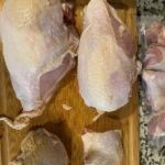 Raw chicken pieces on a wooden cutting board for food prep.