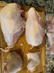 Raw chicken pieces on a wooden cutting board for food prep.