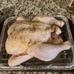Raw whole chicken on a baking tray ready for cooking.