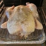 Digital food thermometer on cooked turkey in roasting pan for precise temperature monitoring.