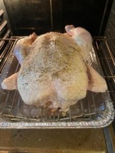 Digital food thermometer on cooked turkey in roasting pan for precise temperature monitoring.
