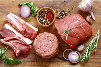 Assorted raw meats with herbs and spices for grilling or cooking.