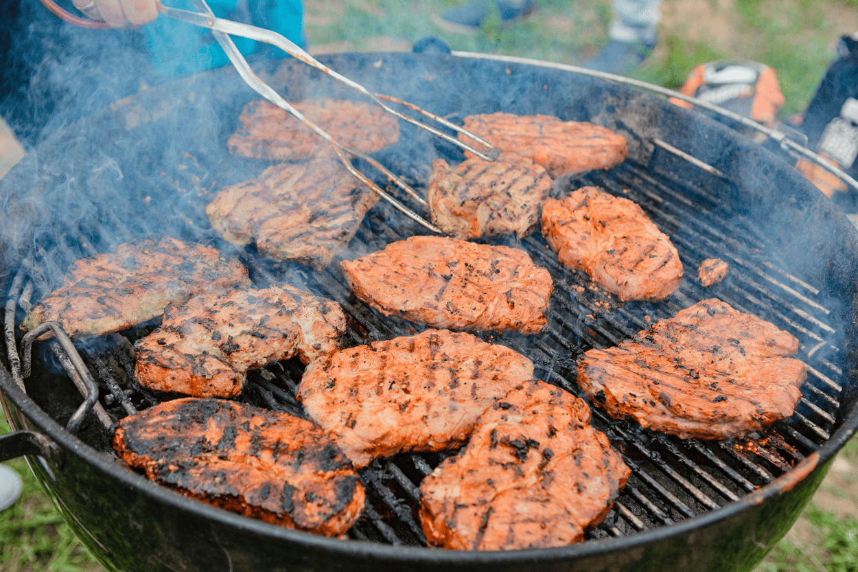 Juicy grilled steaks cooking on a barbecue, perfect for outdoor grilling and culinary enthusiasts.