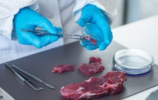 Precision kitchen thermometer testing raw meat for safe cooking temperature.