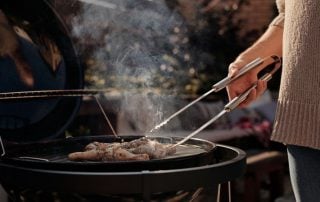 Grilling meat outdoors with stainless steel tongs for perfect barbecue cooking.