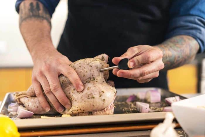 Precision meat thermometer testing a seasoned whole chicken for cooking perfection.