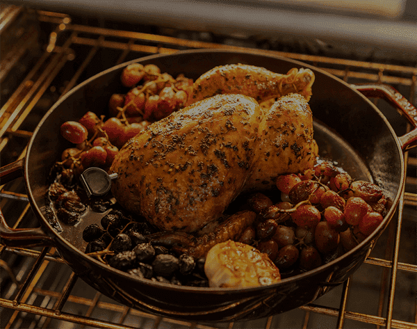 Juicy roasted chicken with grapes cooking in oven.