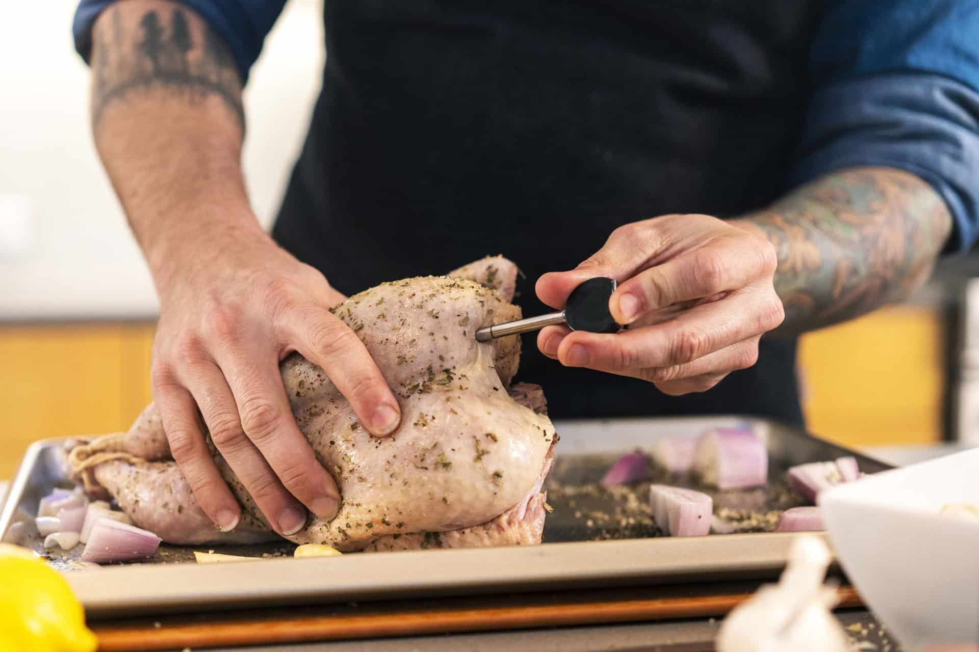 Precision cooking of a seasoned whole chicken using a digital thermometer for perfect doneness.