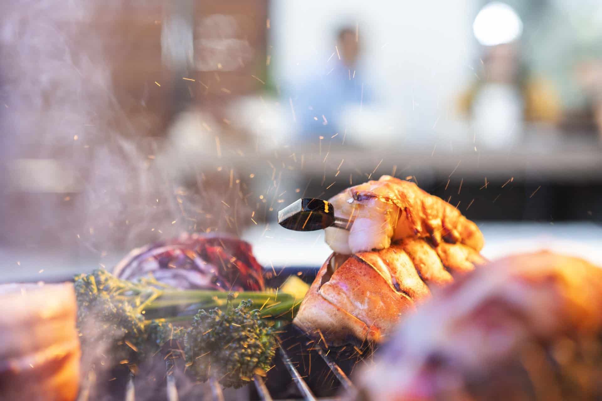 Sizzling lobster tail being grilled at Chef's Temp catering, showcasing seafood cooking techniques.