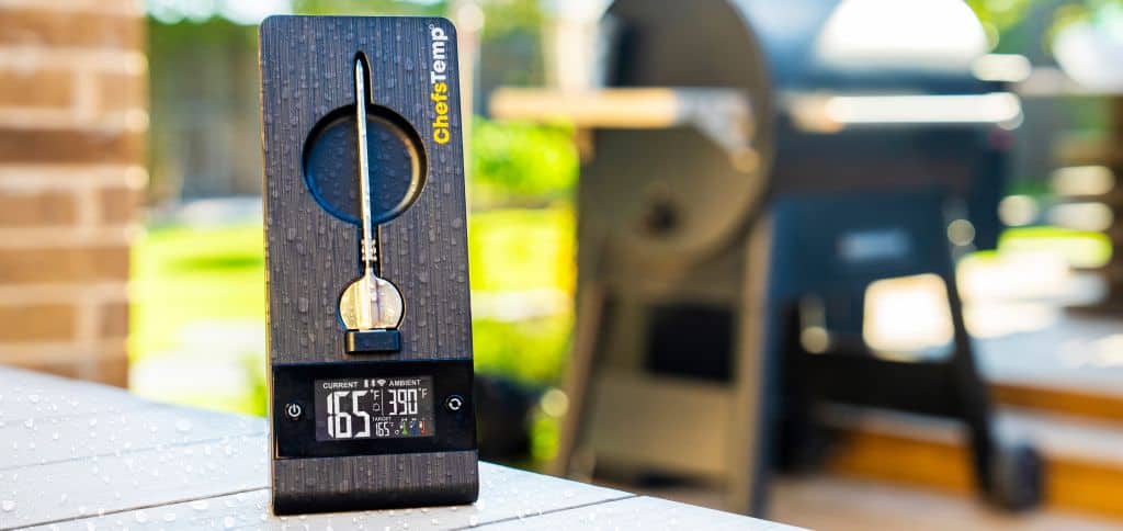 Digital meat thermometer on a wooden table outdoors, ideal for grilling and bbq.