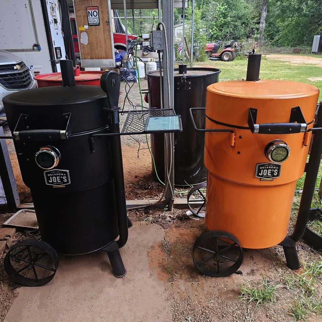 Black and orange insulated outdoor smokers on wheels, ideal for barbeque competitions and outdoor cooking.