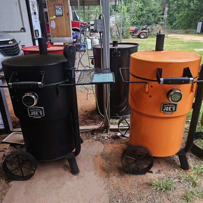 Black and orange insulated outdoor smokers on wheels, ideal for barbeque competitions and outdoor cooking.