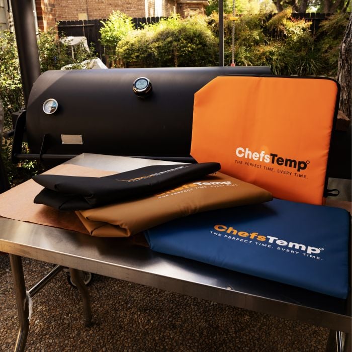 Collection of ChefsTemp grilling accessories and covers displayed on a barbecue table outdoors.
